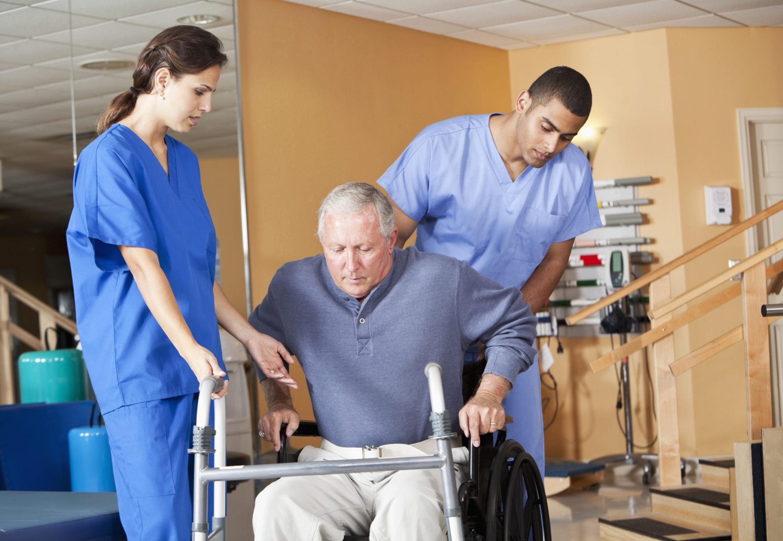 Healthcare professionals are helping senior men (60s) stand up from a wheelchair to use walkers